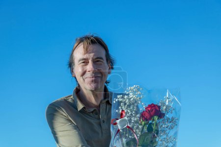 Photo for Senior man holding a bouquet of flowers with red roses to offer a gift of love - Royalty Free Image