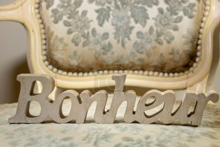 Carved in the wood, the word happiness on a bergere gray fabric, shabby chic