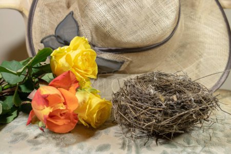 En el tocador, las rosas y el nido de pájaro colocados junto al sombrero de paja de Madame