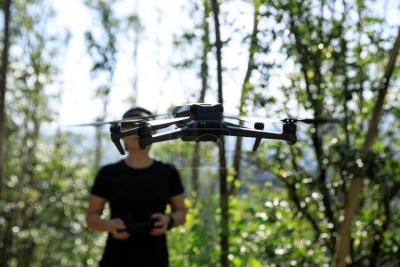 Foto de People remote control a flying drone in summer forest - Imagen libre de derechos