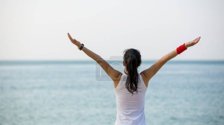 Téléchargez les photos : Jeune femme réussie bras ouverts au bord de la mer - en image libre de droit