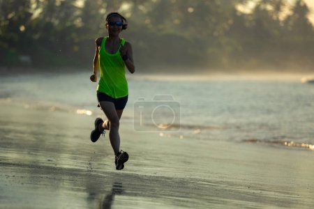 Photo for Healthy lifestyle young fitness woman running on sunrise beach - Royalty Free Image
