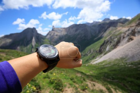 Téléchargez les photos : Randonneur au sommet d'une montagne de haute altitude vérifiant l'altimètre sur la montre de sport - en image libre de droit