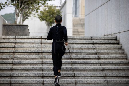 Téléchargez les photos : Femme de remise en forme courant dans les escaliers de la ville - en image libre de droit