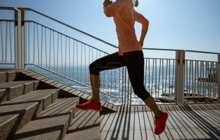 Foto de Estilo de vida saludable fitness corredor de deportes mujer corriendo por sendero costero - Imagen libre de derechos