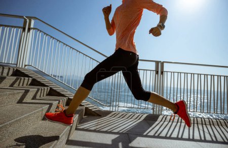 Foto de Estilo de vida saludable fitness corredor de deportes mujer corriendo por sendero costero - Imagen libre de derechos