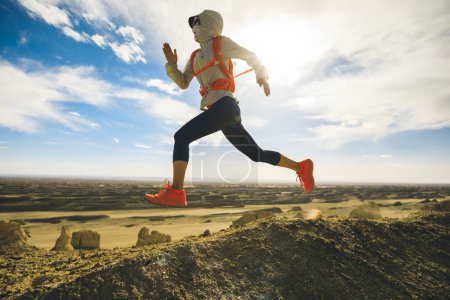 Foto de Mujer trail runner cross country running on desert hill top - Imagen libre de derechos