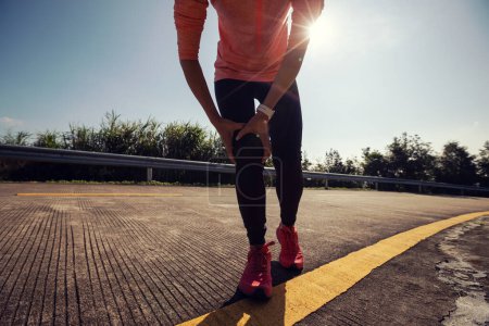 Foto de Joven corredor femenino tiene lesiones deportivas en la rodilla - Imagen libre de derechos
