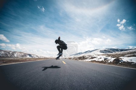 Photo for Asian woman skateboarder skateboarding on snowy country road - Royalty Free Image