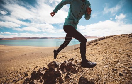 Foto de Mujer trail runner cross country running in lakeside mountains - Imagen libre de derechos