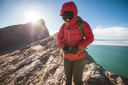Téléchargez les photos : Femme randonneur boucle la ceinture de sac à dos sur le sommet de la montagne - en image libre de droit
