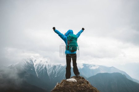 Foto de Mujer excursionista disfrutar de la vista en la cima de la montaña acantilado frente a las montañas nevadas en el Tíbet - Imagen libre de derechos