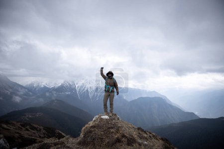 Photo for Successful woman hiker stand at mountain top cliff edge background the snow capped mountains in tibet - Royalty Free Image