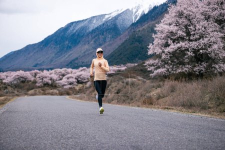 Photo for Woman running in peach flowers blooming tibet, China - Royalty Free Image