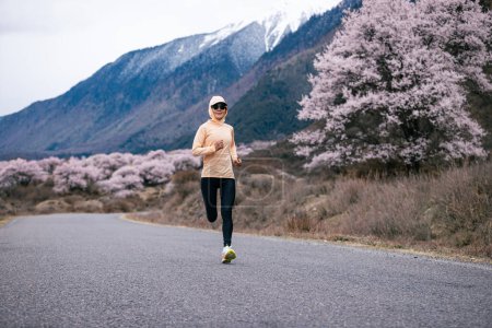Photo for Woman running in peach flowers blooming tibet, China - Royalty Free Image