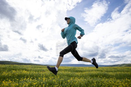 Foto de Mujer trail runner cross country corriendo en pastizales de gran altitud - Imagen libre de derechos