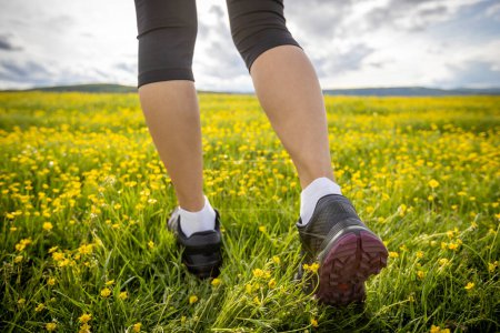 Photo for Woman runner legs on flowers trail on high altitude grassland - Royalty Free Image