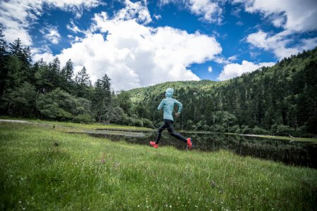 Téléchargez les photos : Femme coureuse de trail cross country courir dans de belles prairies - en image libre de droit