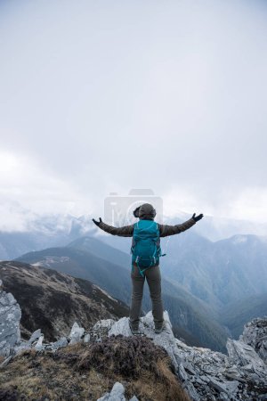 Téléchargez les photos : Femme randonneur profiter de la vue sur le sommet de la falaise face aux montagnes enneigées au Tibet - en image libre de droit