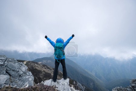 Photo for Woman hiker enjoy the view on mountain top cliff edge face the snow capped mountains in tibet - Royalty Free Image