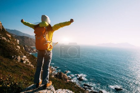 Téléchargez les photos : Succès femme randonneur debout sur le lever du soleil bord de la falaise de montagne - en image libre de droit