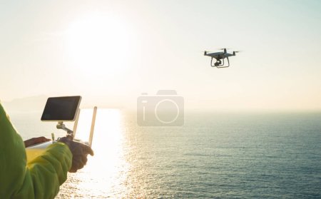 Foto de Silueta de control remoto un dron volador que toma fotos sobre el mar amanecer - Imagen libre de derechos