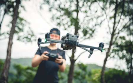 Téléchargez les photos : People remote control a flying drone in summer forest - en image libre de droit