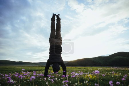 Téléchargez les photos : Femme randonneur faisant un handstand sur prairie de montagne de haute altitude - en image libre de droit