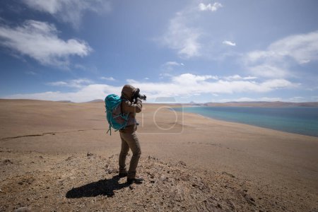 Photo for Woman photographer taking phtoto hiking in beautiful winter high altitude mountains - Royalty Free Image