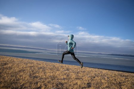 Foto de Mujer trail runner cross country running in lakeside mountains - Imagen libre de derechos