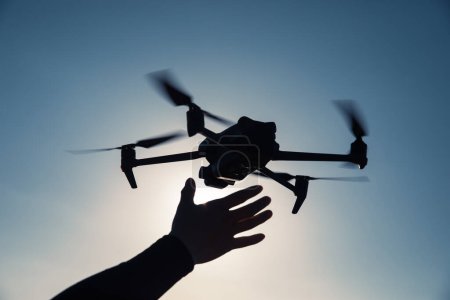 Téléchargez les photos : Silhouette de drone volant prenant des photos au lever du soleil - en image libre de droit