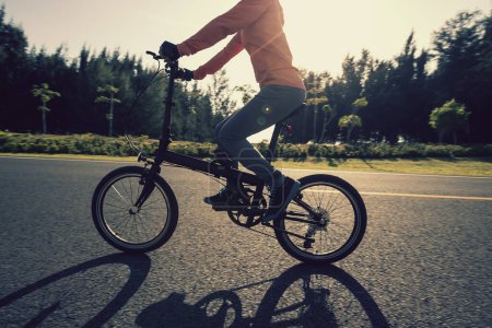 Riding folding bike on sunny seaside road