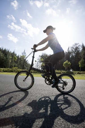 Photo for Riding folding bike on sunny seaside road - Royalty Free Image