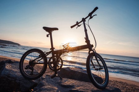 Photo for A  folding bike on sunrise seaside road - Royalty Free Image