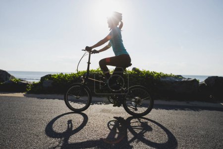 Photo for Riding folding bike on sunrise seaside road - Royalty Free Image