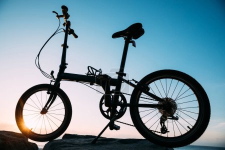 Téléchargez les photos : Un vélo pliant sur la route côtière du lever du soleil - en image libre de droit