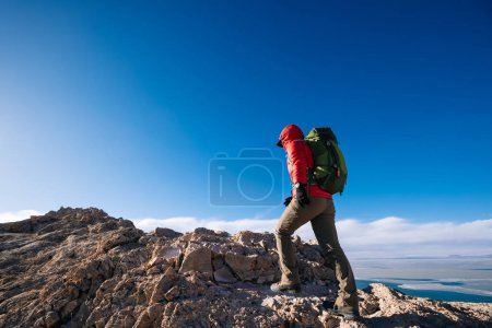 Téléchargez les photos : Femme randonneur escalade au sommet de la falaise au bord du lac - en image libre de droit