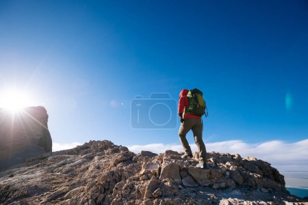 Foto de Mujer excursionista escalada a la cima de la montaña borde del acantilado en la orilla del lago - Imagen libre de derechos