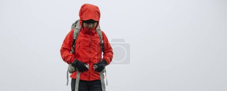 Téléchargez les photos : Femme randonneur boucle la ceinture de sac à dos sur le sommet de la montagne - en image libre de droit