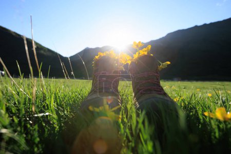 Photo for Hiking boots with yellow wild flowers in grass - Royalty Free Image