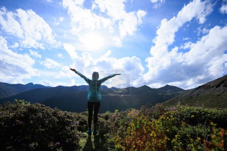 Téléchargez les photos : Femme réussie jambes tendues au sommet de la montagne haute altitude - en image libre de droit