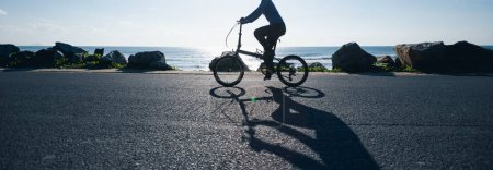 Foto de Montar bicicleta plegable en la salida del sol carretera costera - Imagen libre de derechos