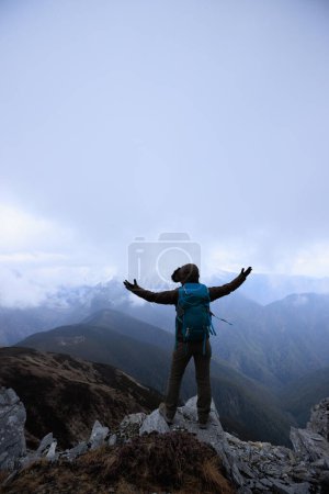 Foto de Mujer excursionista disfrutar de la vista en la cima de la montaña acantilado frente a las montañas nevadas en el Tíbet - Imagen libre de derechos
