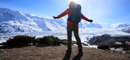Foto de Mujer excursionista disfrutar de la vista en la cima de la montaña acantilado cara a las montañas glaciares - Imagen libre de derechos