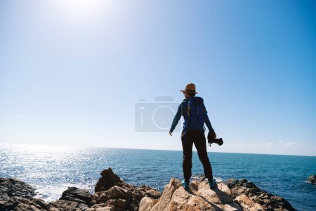 Photo for Woman photographer enjoy the view on sunrise seaside rocks - Royalty Free Image