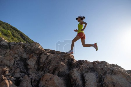 Foto de Corredor mujer corriendo al amanecer en las montañas rocosas junto al mar - Imagen libre de derechos