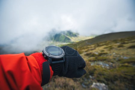 Foto de Mujer excursionista comprobando la altitud en smartwatch en pico de montaña - Imagen libre de derechos