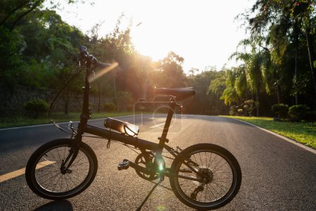Téléchargez les photos : Un vélo pliant sur la route du coucher du soleil - en image libre de droit