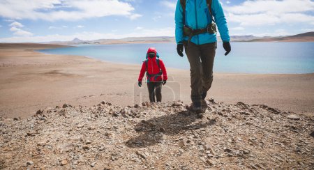 Photo for Two women backpackers hiking in beautiful winter high altitude mountains - Royalty Free Image