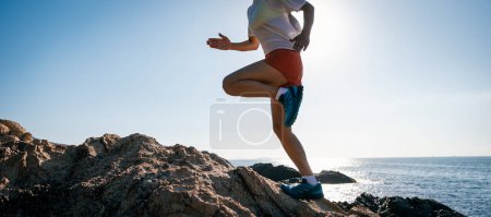 Téléchargez les photos : Femme coureuse qui court sur les rochers du lever du soleil - en image libre de droit